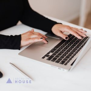 Assistant werkt geconcentreerd achter een laptop, symbool voor de professionaliteit en het goede werkgeverschap achter de SNA-certificering van Secretary House